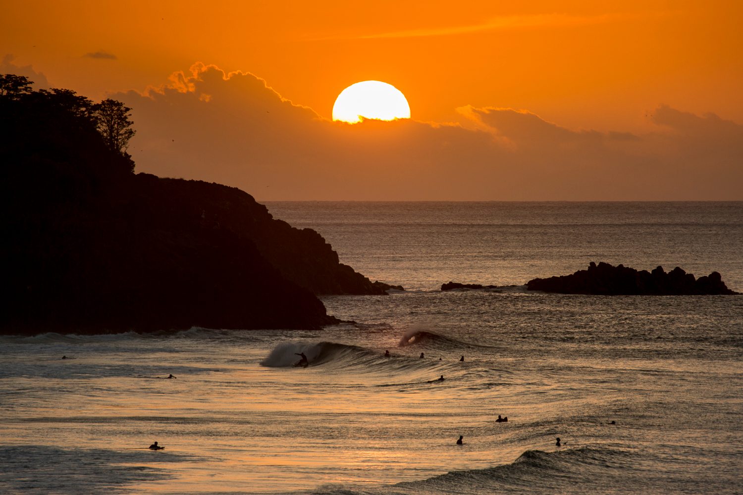 Sun setting above waves on a rocky coast