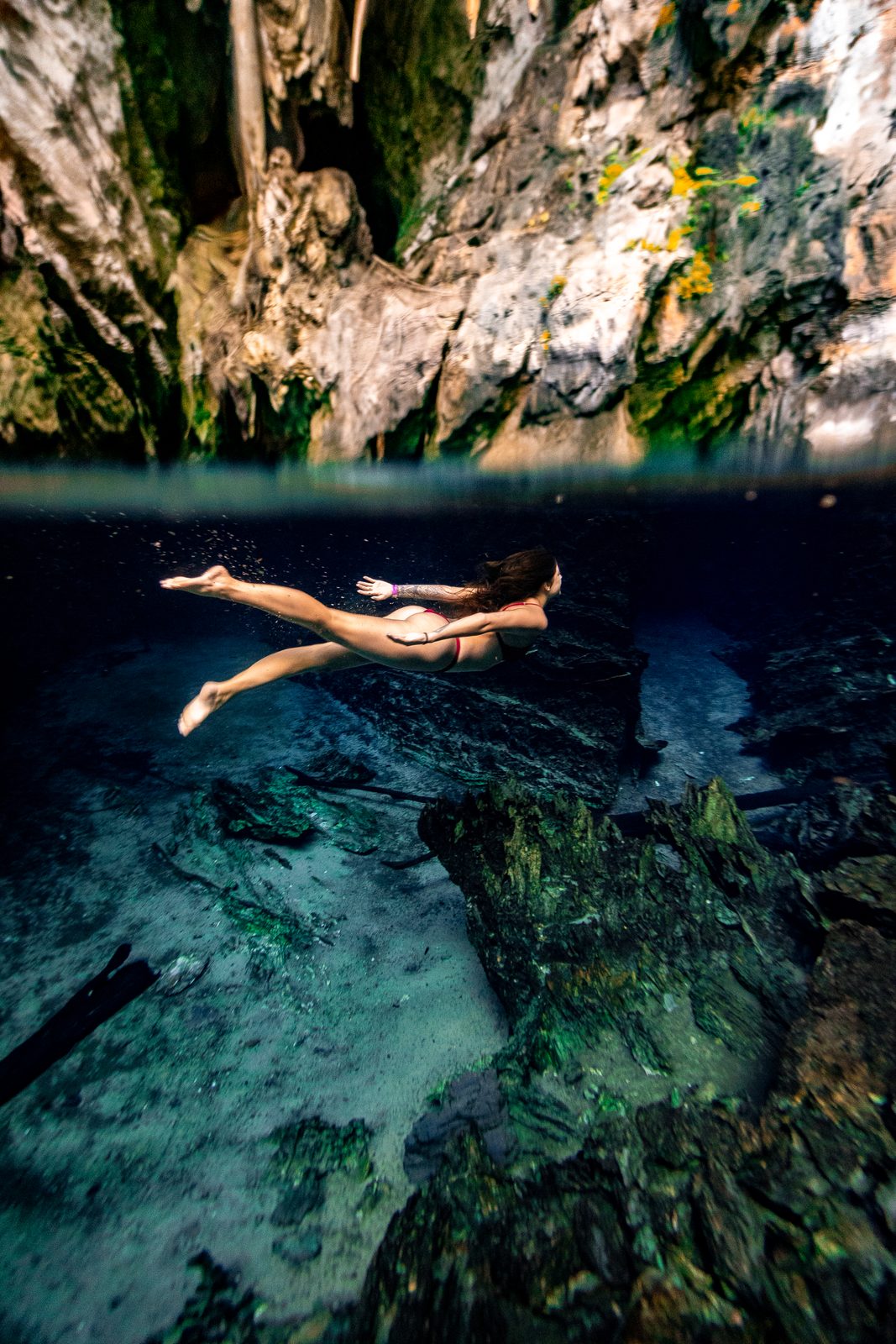 Swimmer floating in a clear pool between rock walls