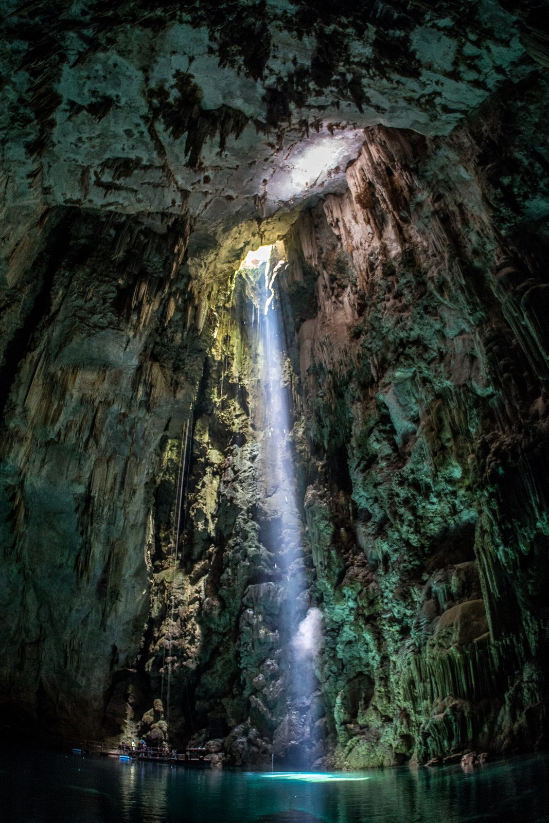 Narrow waterfall falling through a shadowed rocky grotto